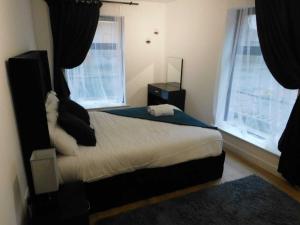 2 Bed Modern Apartment Manchester City Centre في مانشستر: غرفة نوم بسرير ونوافذ