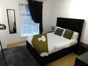 2 Bed Modern Apartment Manchester City Centre في مانشستر: غرفة نوم بسرير كبير ومخدات خضراء وبيضاء