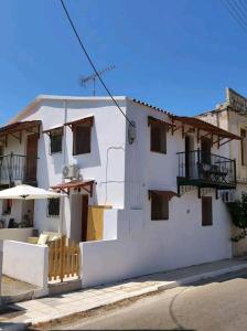 a white building with a balcony and an umbrella at Nikόla's House in Mourniaí