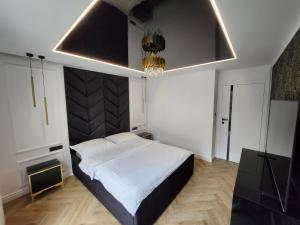 a bedroom with a large bed and a chandelier at Marina Apartments in Gdańsk