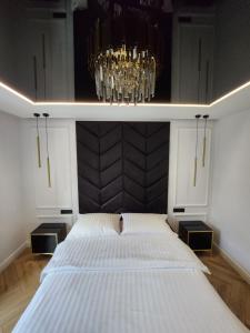 een slaapkamer met een groot bed en een kroonluchter bij Marina Apartments in Gdańsk