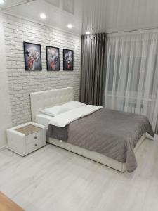 a bedroom with a bed and a white brick wall at Дизайнерская квартира в центре города in Petropavlovsk