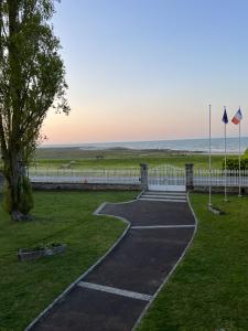 Una pasarela en un parque con el océano al fondo en La Salmonière, en Le Vivier-sur-Mer