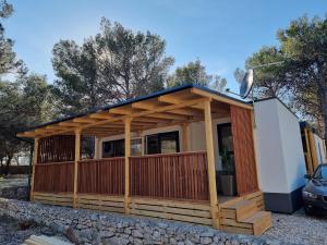 a small house with a deck on a rock at Premium mobile home SUN & JOY - Oaza Mira Camping in Drage