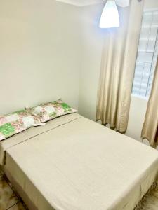 uma cama num quarto branco com uma janela em Apartamento Mobiliado em Limeira em Limeira