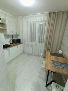 cocina con armarios blancos y mesa de madera en Дизайнерская квартира в центре города, en Petropavlovsk