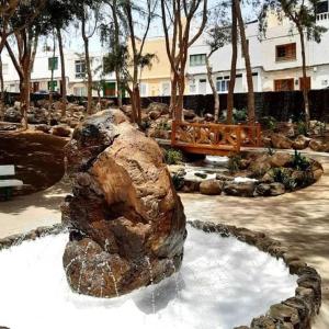 Una gran roca sentada en una fuente en un parque. en Apartamento jable, en Arrecife