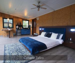 een slaapkamer met een groot bed en een blauwe deken bij Magma "Eco Hotel Cabañas" in La Vega