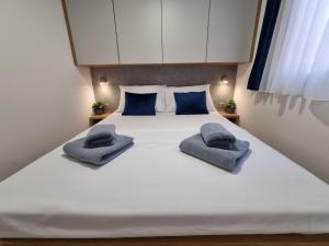 Premium mobile home SUN & JOY - Oaza Mira Camping في دراغ: سرير أبيض كبير مع وسادتين زرقاوين عليه