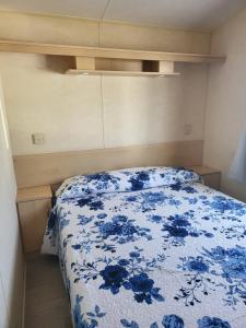 a bedroom with a bed with a blue floral bedspread at camping Pradon in Arnuero