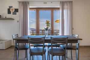 a dining room table with chairs and a large window at Agriturismo Bocca Nevese Abete in Tremosine Sul Garda
