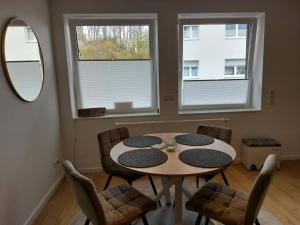 a dining room with a table and chairs and two windows at Ferienwohnung Kreuztal in Kreuztal