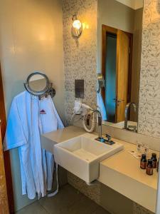 a bathroom with a sink and a mirror at Hotel Piratininga Avenida Amazonas - Rondonópolis in Rondonópolis
