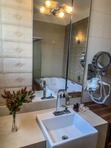 a bathroom with a sink and a large mirror at Hotel Piratininga Avenida Amazonas - Rondonópolis in Rondonópolis
