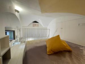 ein Schlafzimmer mit einem Bett mit gelbem Kissen darauf in der Unterkunft Casa iuserì in Cisternino