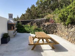 un banco de madera sentado en un patio junto a una pared de piedra en Casa Armonía del Silencio, en Valverde
