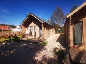 a wooden cabin with a deck and a fence at Sea You Soon w Sztutowie in Sztutowo
