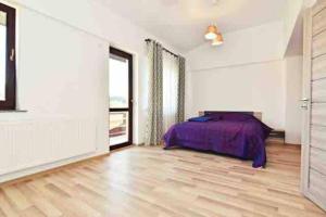 1 dormitorio blanco con 1 cama y suelo de madera en Casa Albert, en Iaşi