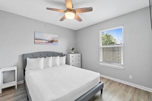 um quarto branco com uma cama e uma ventoinha de tecto em Beach House - Moasis by Panhandle Getaways em Panama City Beach