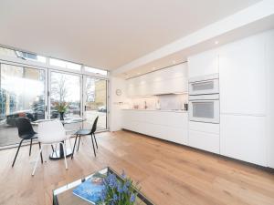 cocina con armarios blancos, mesa y sillas en Modern Luxury 1 Bedroom Spacious Flat en Londres