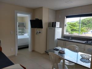 a kitchen with a refrigerator and a table with chairs at Pousada Bella Bombinhas - Pé na areia in Bombinhas