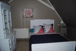una camera da letto con un letto bianco con cuscini rossi di La Ferme aux Fleurs a Ossun