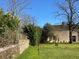 a yard with a stone fence and a house at Blue Lotus Gite et Spa in Le Langon