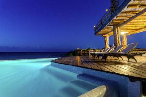 a swimming pool with chairs on a deck with the ocean at DK Luxury Ocean Front Villa - Adults Only in Holbox Island