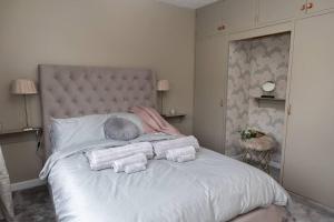 um quarto com uma cama branca e toalhas em The Menapian House Enniskillen em Killyhevlin