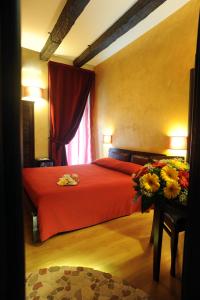 a bedroom with a red bed with flowers on a table at B&B Muro Torto Cairoli - Struttura sanificata giornalmente con prodotti specifici conformi al Decalogo del Ministero Salute - Personale sottoposto a test sierologico periodicamente in Foggia