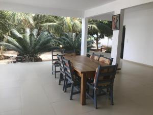 a wooden table and chairs in a room with palm trees at Villa chez ibou somone in Somone