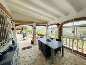 eine Küche mit einem Tisch, Stühlen und Fenstern in der Unterkunft Villa Casira met 2 studio's - 10 personen, Viñuela, Costa Del Sol in Viñuela