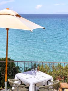 - une table avec un parasol, des chaises et l'océan dans l'établissement Misincu, à Cagnano