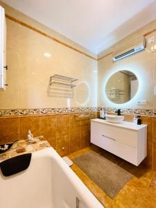 ein Badezimmer mit einer Badewanne, einem Waschbecken und einem Spiegel in der Unterkunft Villa Casira met 2 studio's - 10 personen, Viñuela, Costa Del Sol in Viñuela
