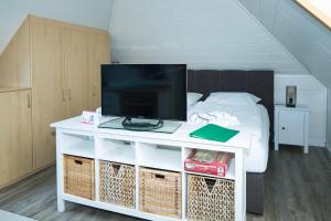 Un televisor sobre una mesa blanca en una habitación con una cama. en Haus Mühlentrift Döse, en Cuxhaven 36 fotos más