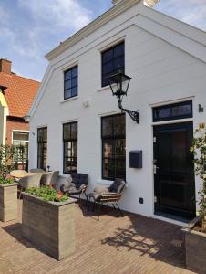 a white house with black windows and a patio at Appartement Badnieuweschans in Bad-Nieuweschans