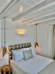 una camera da letto con un letto bianco con cuscini bianchi di Sofos Suites Mykonos a Mykonos Città
