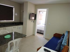 a kitchen and living room with a couch and a table at Pousada Bella Bombinhas - Pé na areia in Bombinhas