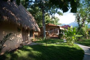 a house with a grass roof and a yard at Kuda Laut Bungalows & Diving in Pemuteran
