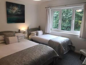 two beds in a room with two windows at Snowdonia Mawddach escape in Dolgellau