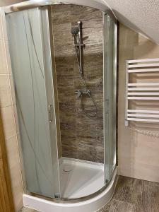 a shower with a glass door in a bathroom at Apartament na poddaszu u Reni in Grywałd