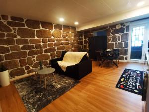 a living room with a stone wall at Alojamento Local F&B in Guimarães