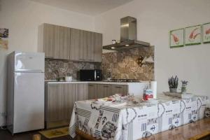 uma cozinha com uma mesa e um frigorífico branco em Bilocale Fronte Mare Sparaglione em Sassari