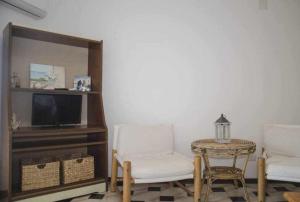 uma sala de estar com duas cadeiras e uma mesa e uma televisão em Bilocale Fronte Mare Sparaglione em Sassari