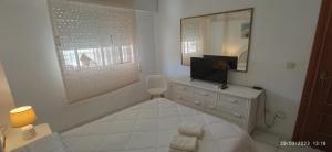 een badkamer met een dressoir met een televisie en een spiegel bij Apartamento Aquarium Park, 1ª linea de playa, para 4 personas in Calpe