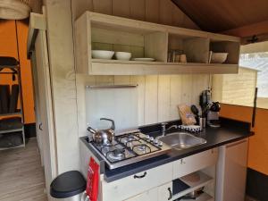 a small kitchen with a stove and a sink at Lodgetent Reisdorf in Reisdorf