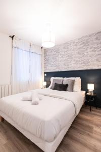 uma grande cama branca num quarto com uma parede em La Parenthèse - Résidence Hestia em Saint-Étienne