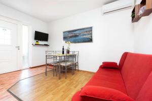 uma sala de estar com um sofá vermelho e uma mesa em Apartment Zaneto em Rovinjsko Selo