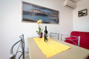 a table with a bottle of wine and a flower on it at Apartment Zaneto in Rovinjsko Selo