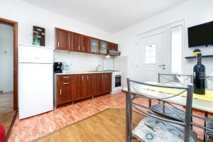 uma cozinha com um frigorífico branco e armários de madeira em Apartment Zaneto em Rovinjsko Selo